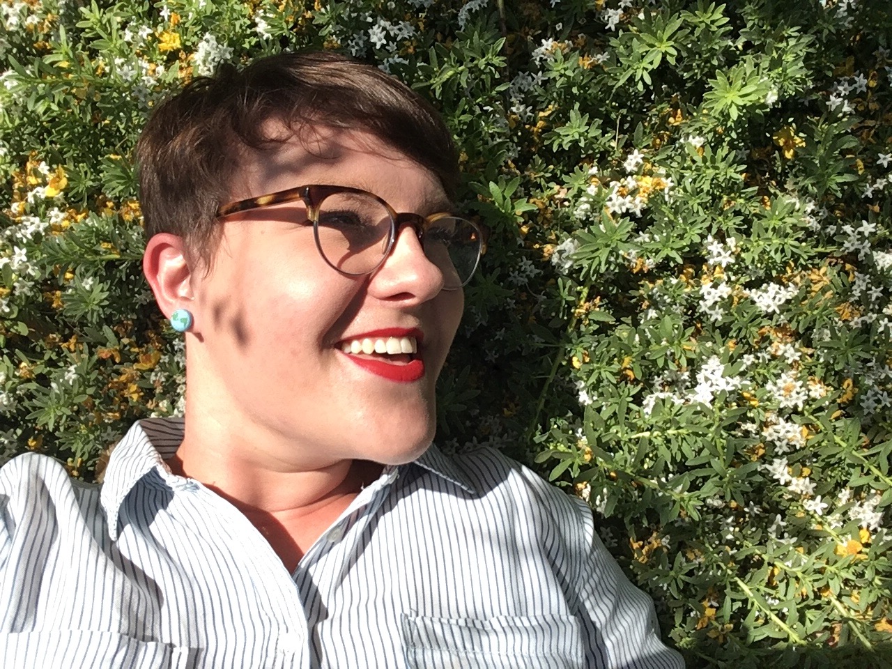 A picture of a person wearing glasses, laying in tiny, white flowers.
