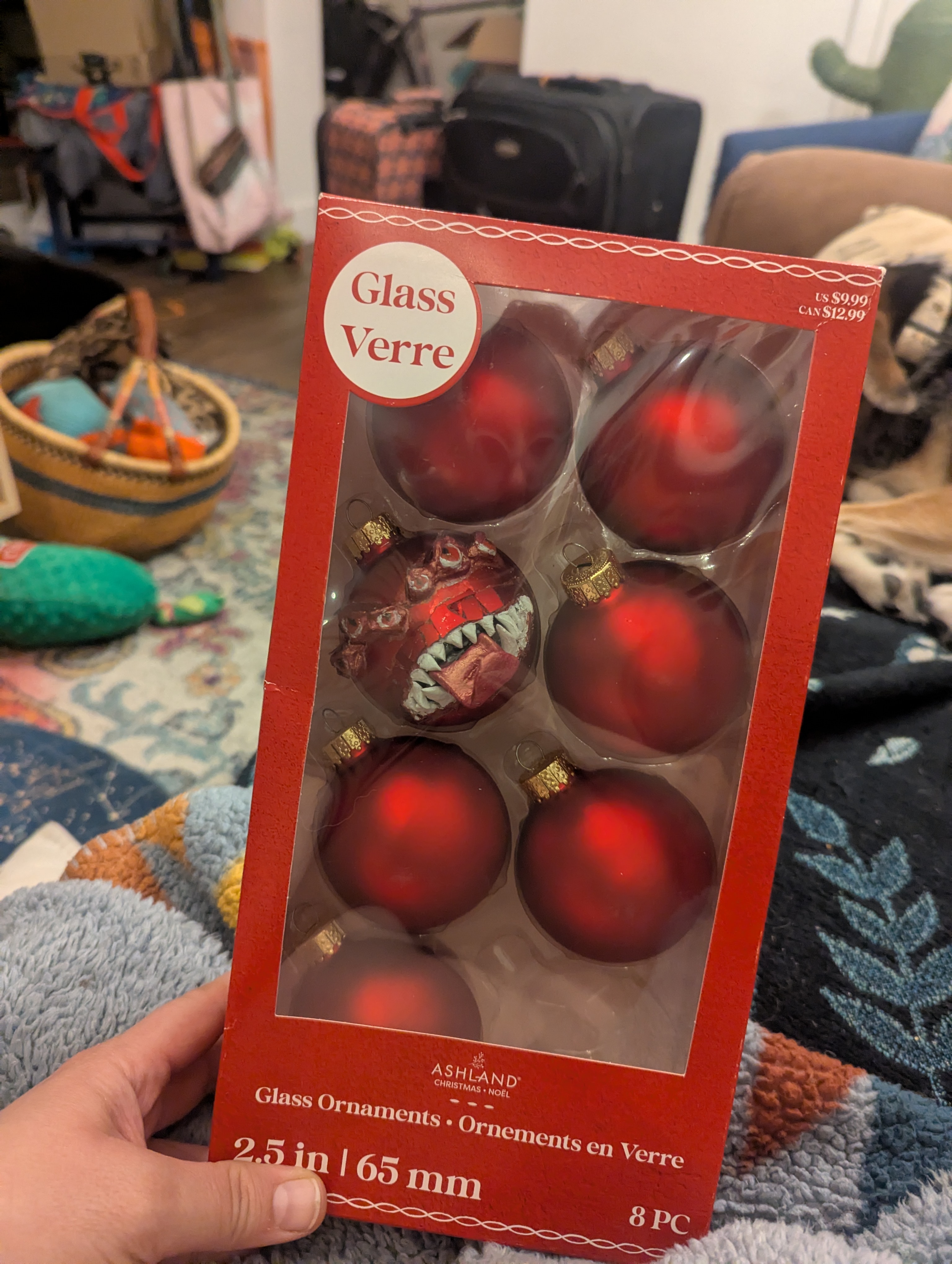 A box of red Christmas ornaments. One ornament has eyes, teeth, and a tongue like a D&D mimic.