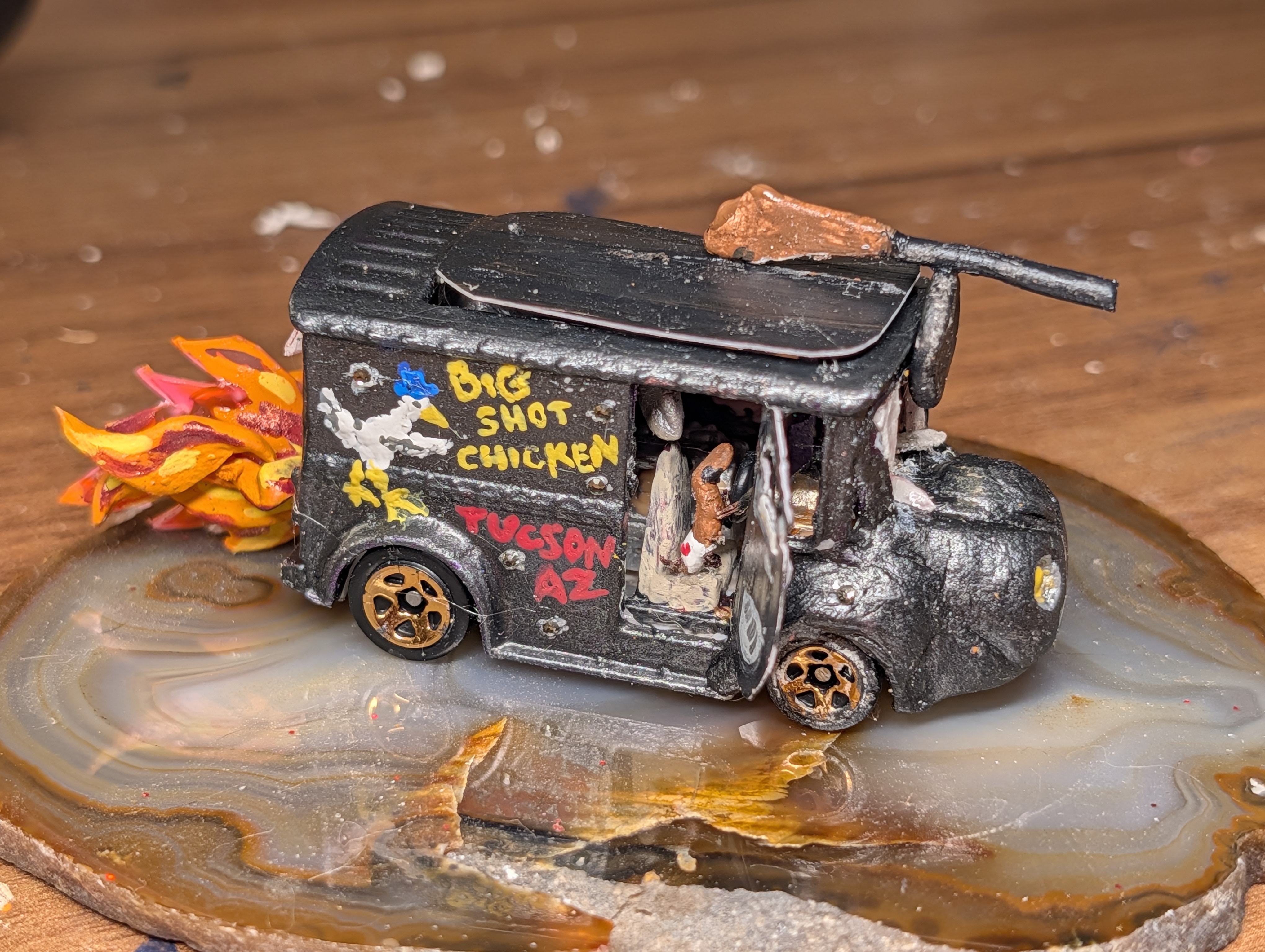 A modded HotWheels foodtruck driven by a heart boxer-wearing dachshund with flames coming out of the back, a tommy gun on the roof, and the words "Big Shot Chicken" painted on the side with the picture of a chicken in a fadora.