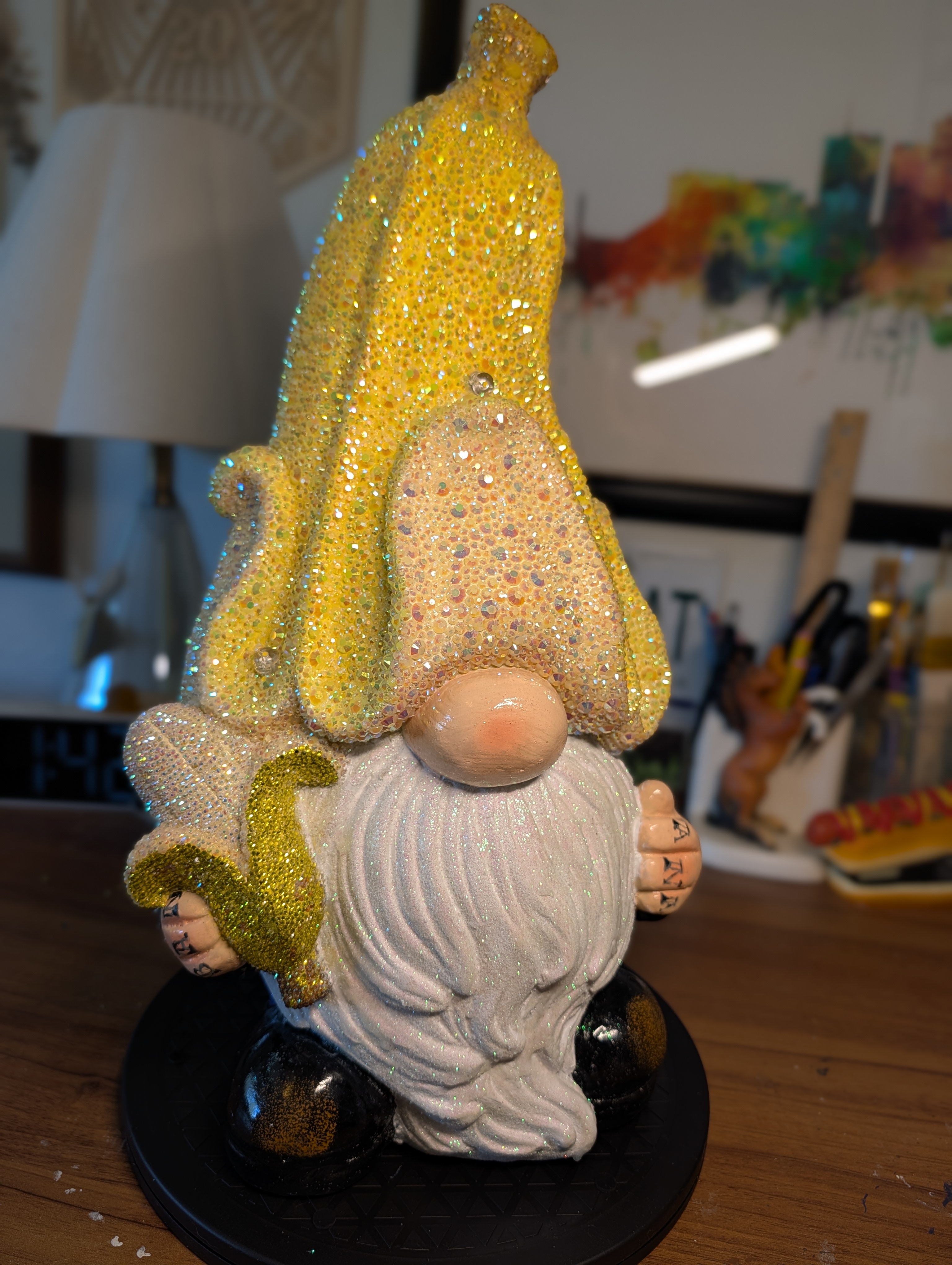 A garden gnome with a banana peel hat holding a banana. The hat and banana have have rhinestoned.